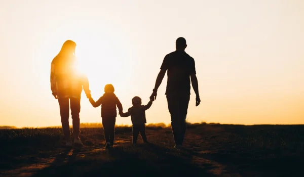 Famiglia mano nella mano passeggia al tramonto