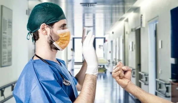 Infermiere con mani alzate minacciato con un pugno